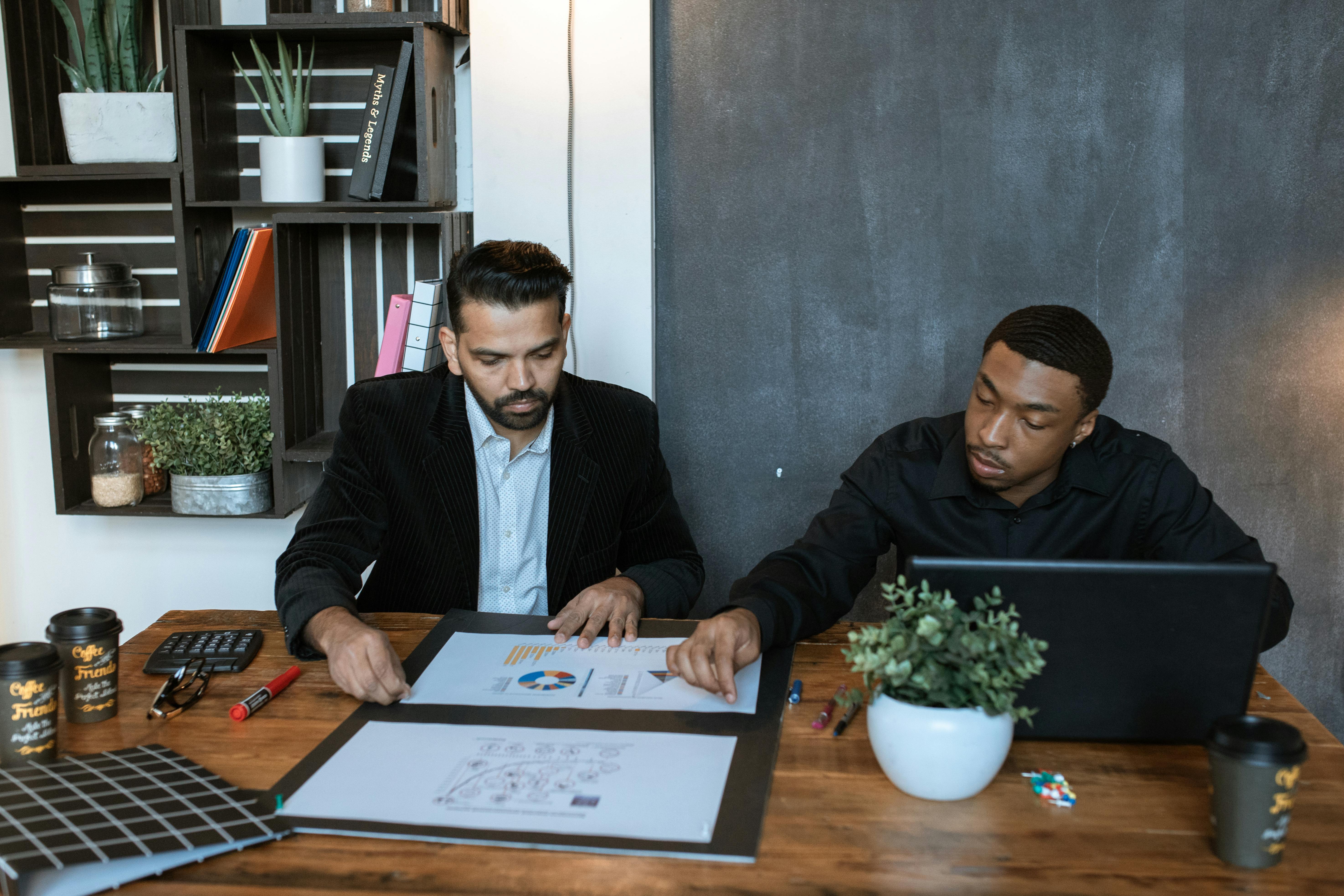 [A pharmacist and care home manager reviewing a medicines chart together at a desk in a residential facility office]